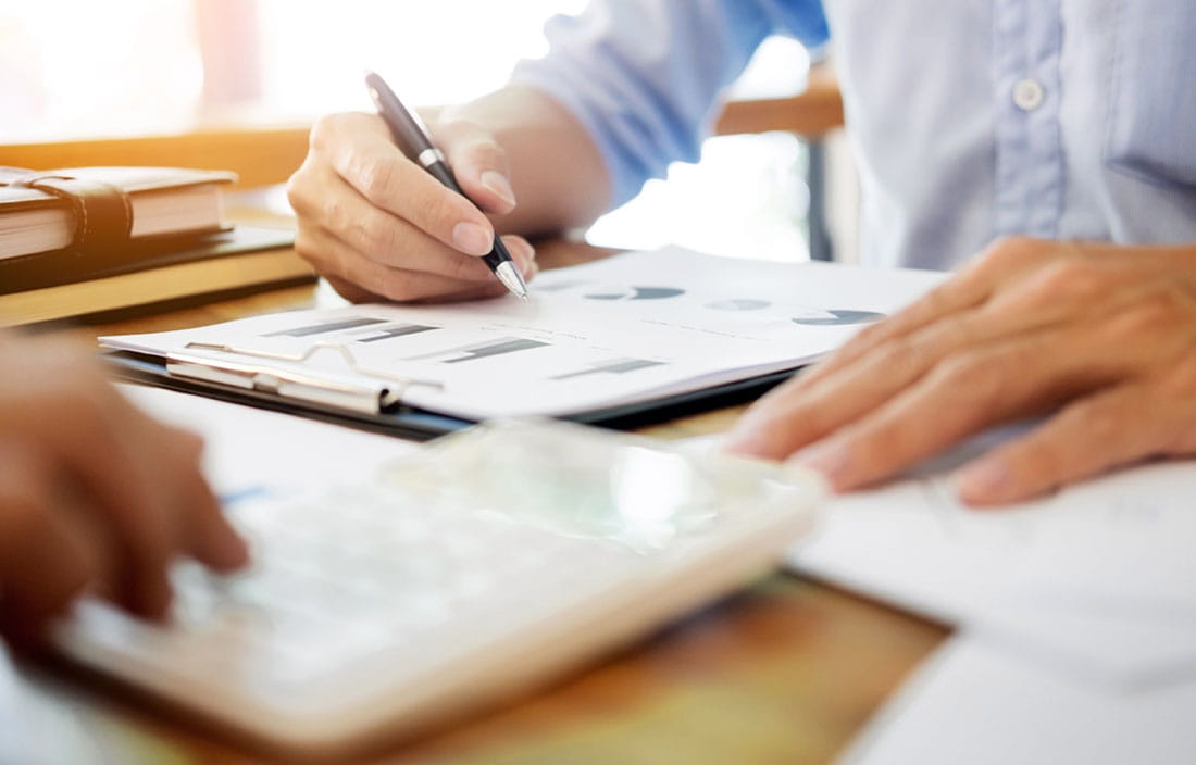 Photo of two people working on tax paperwork together.