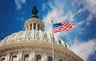 Washington capitol with American flag flying in front of it. 