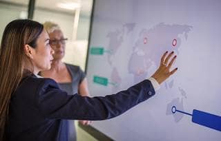 Two women looking at a global map. 