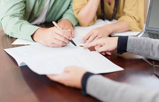 Close-up image of three people's hand, reviewing documents.