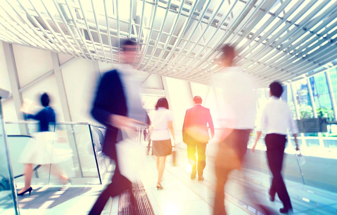 Business people walking trhough a glass walkway/bridge.