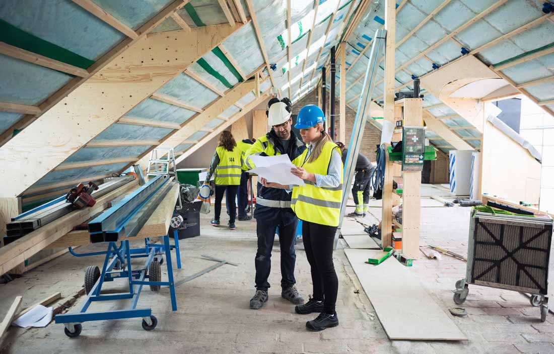 Image of construction workers reading blueprints inside building.