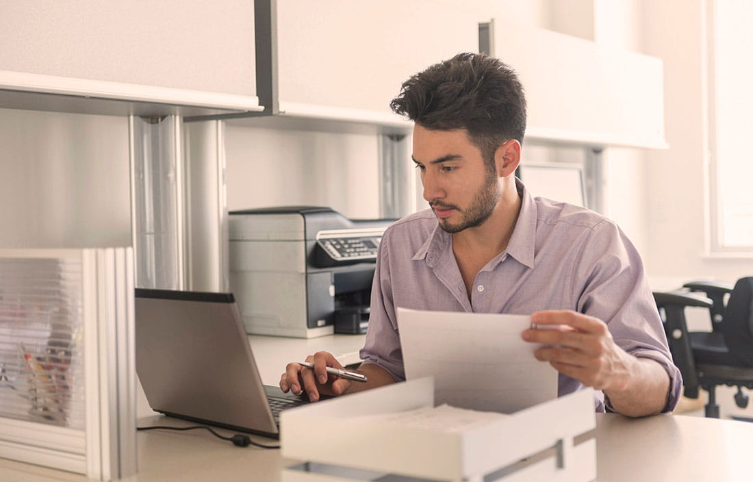 Image of man using computer and going through papers