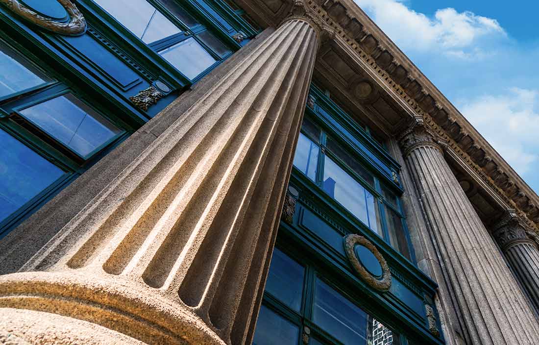 Image of a neo-classical building from the ground perspective looking up.