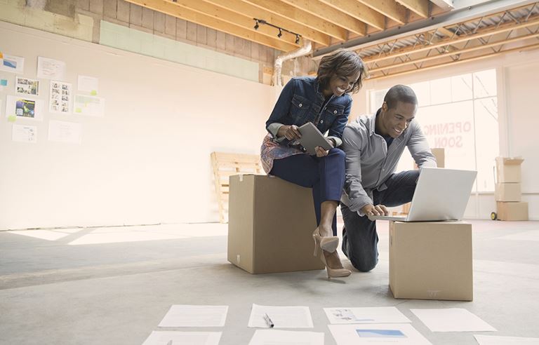 Small business owners discussing employee compensation at a laptop