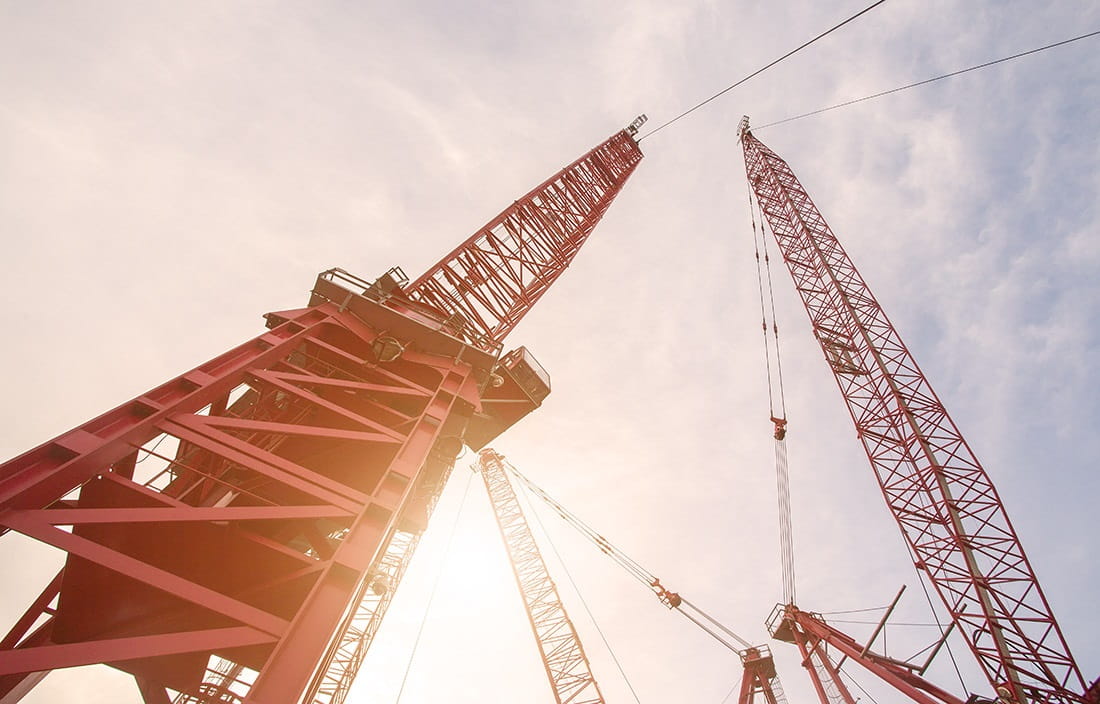 Image of construction cranes, view from the ground looking up to the sky.