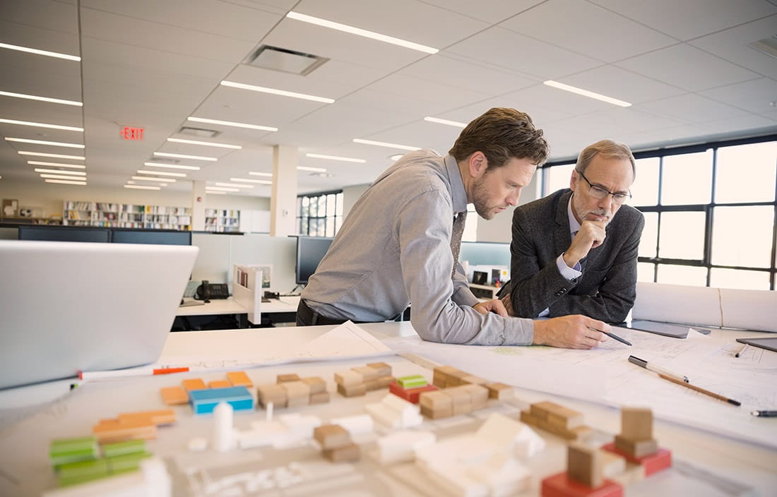 Image of two men in an office reviewing blueprints.