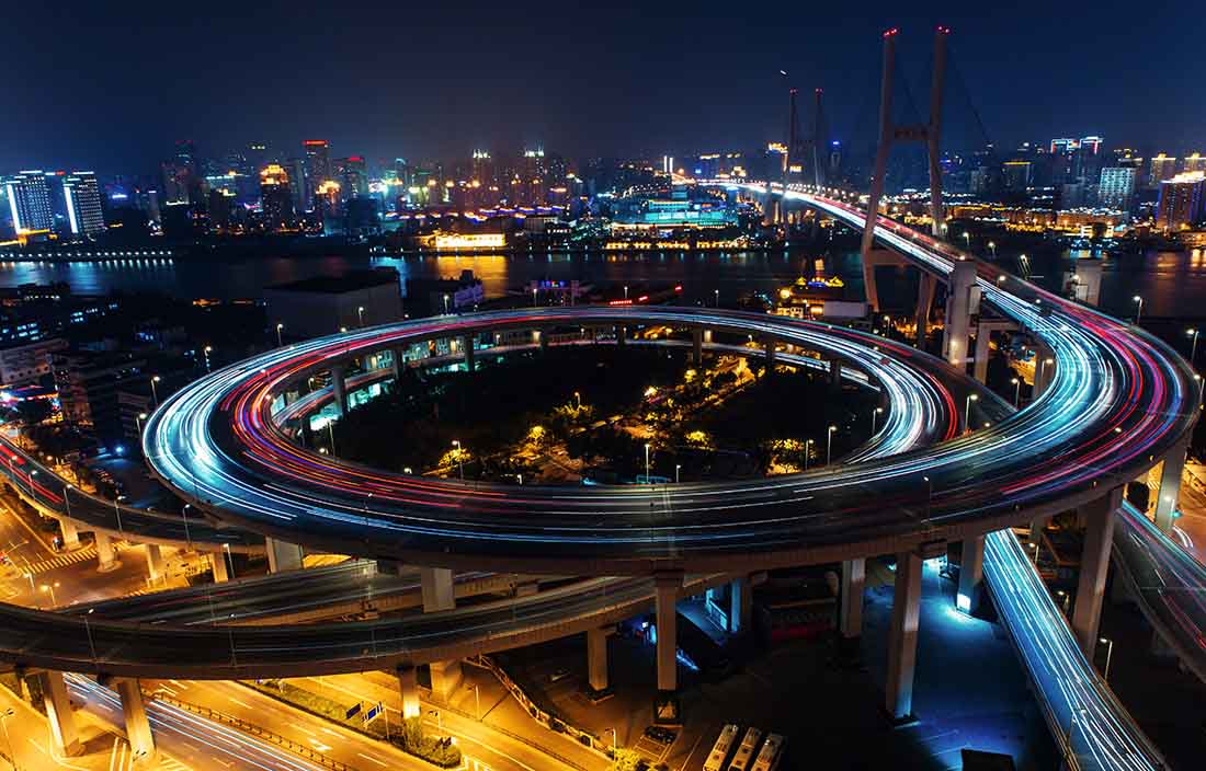 Cars with lights on driving at night on a round city road