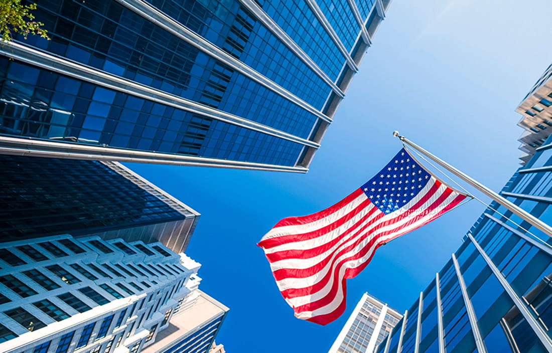 Photo of a U.S. flag nearby tall buildings. 