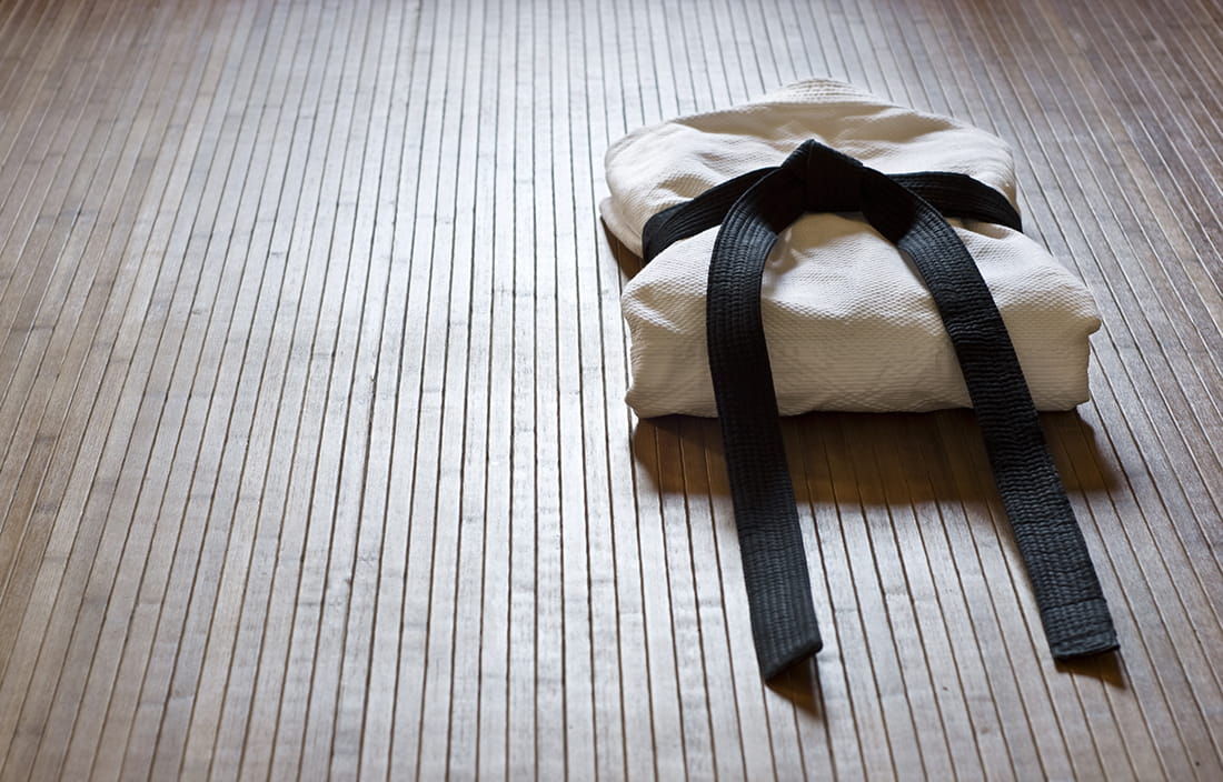 Photo of a martial arts bleck belt on a wooden floor.