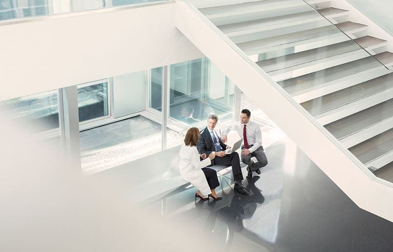 A picture of a lab technician speaking with two businessmen.