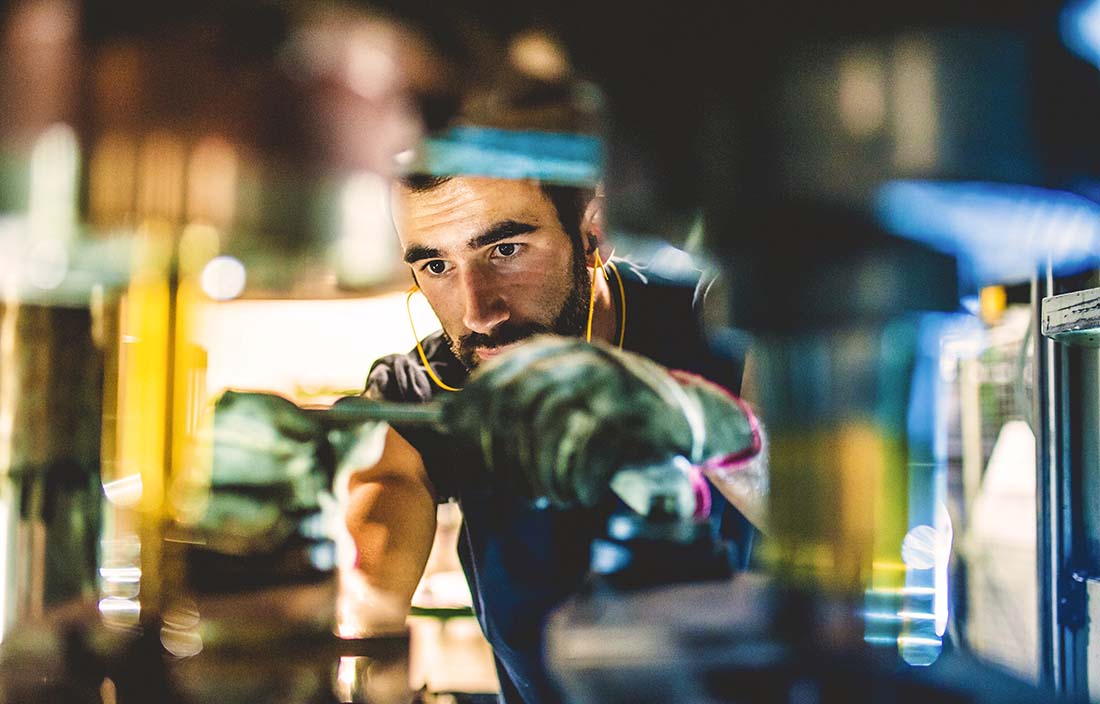 Factory worker at an auto supplier working on a car part.