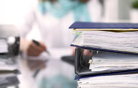 View of a stack of binders and business papers on top of a desk.