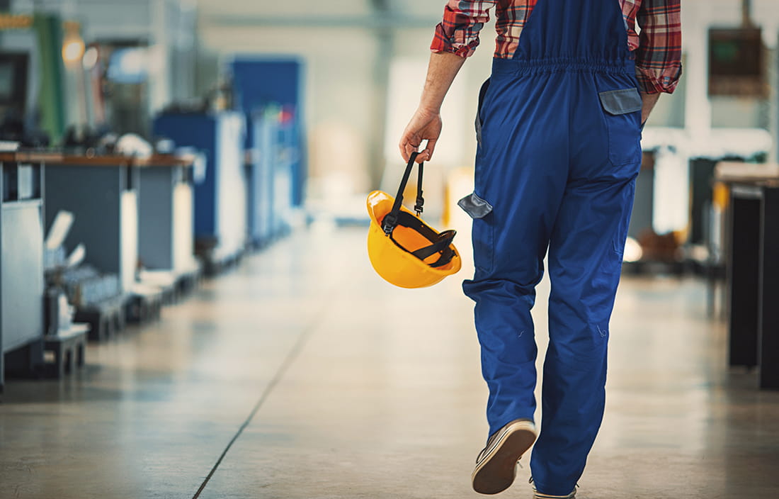 Factory worker carrying hard hat.