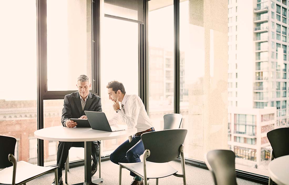 Image of two businessmen at a small table discussing documents.