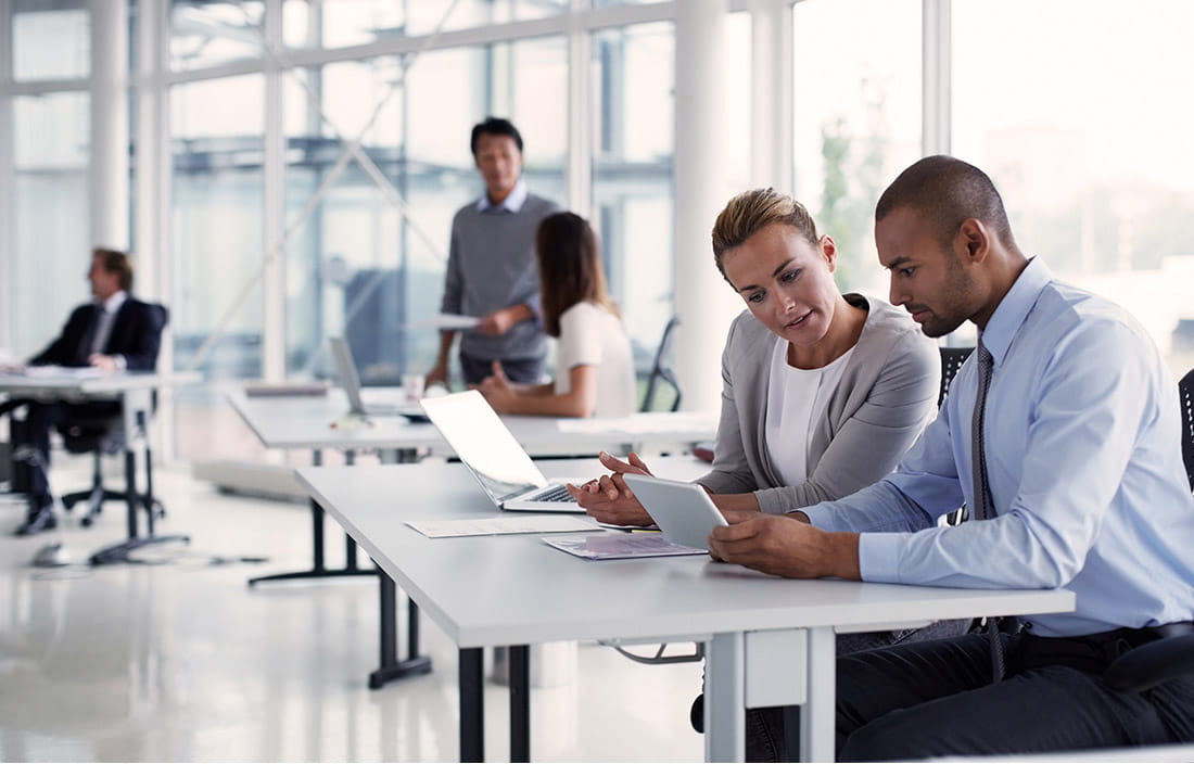 Two CPA professionals looking over and discussing the AICPA's guidance for investment companies.