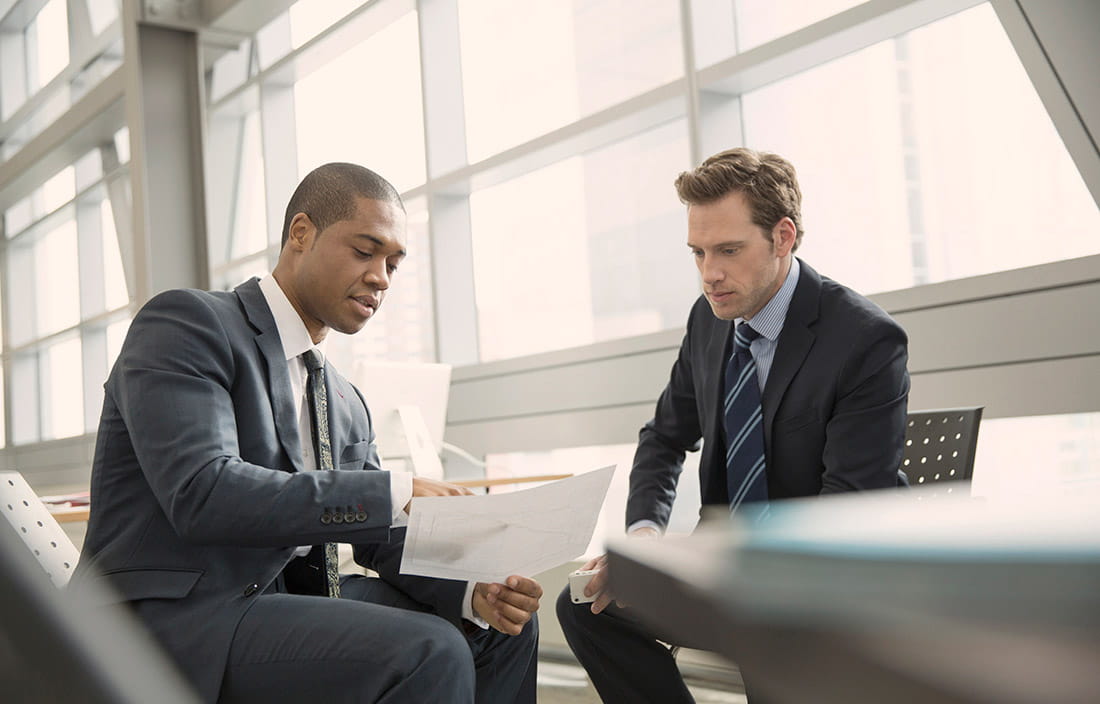 Two business professionals sitting down and discussing covenant loan compliance. 