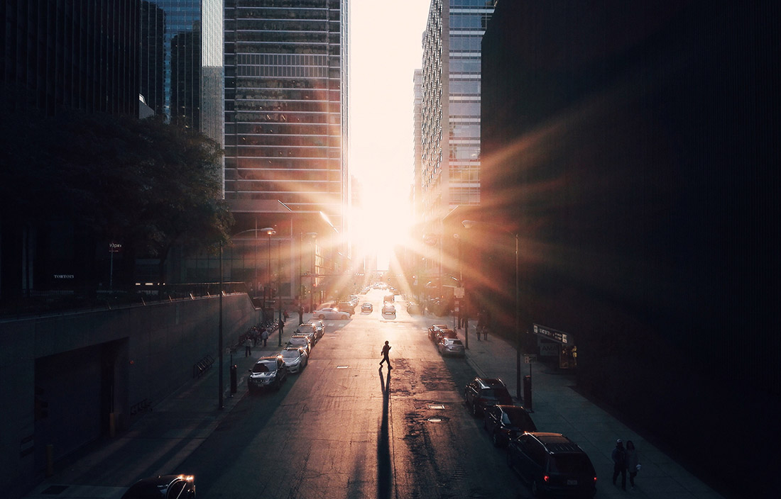 Image of a downtown city street in the early morning, with cars parked along the curb.