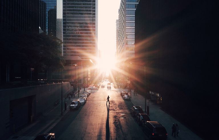 Image of a downtown city street in the early morning, with cars parked along the curb.