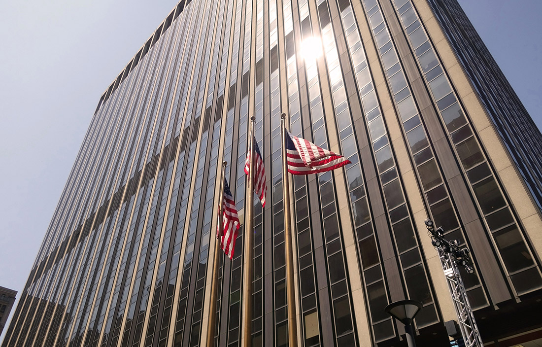Picture of flags in front of a tall business building.
