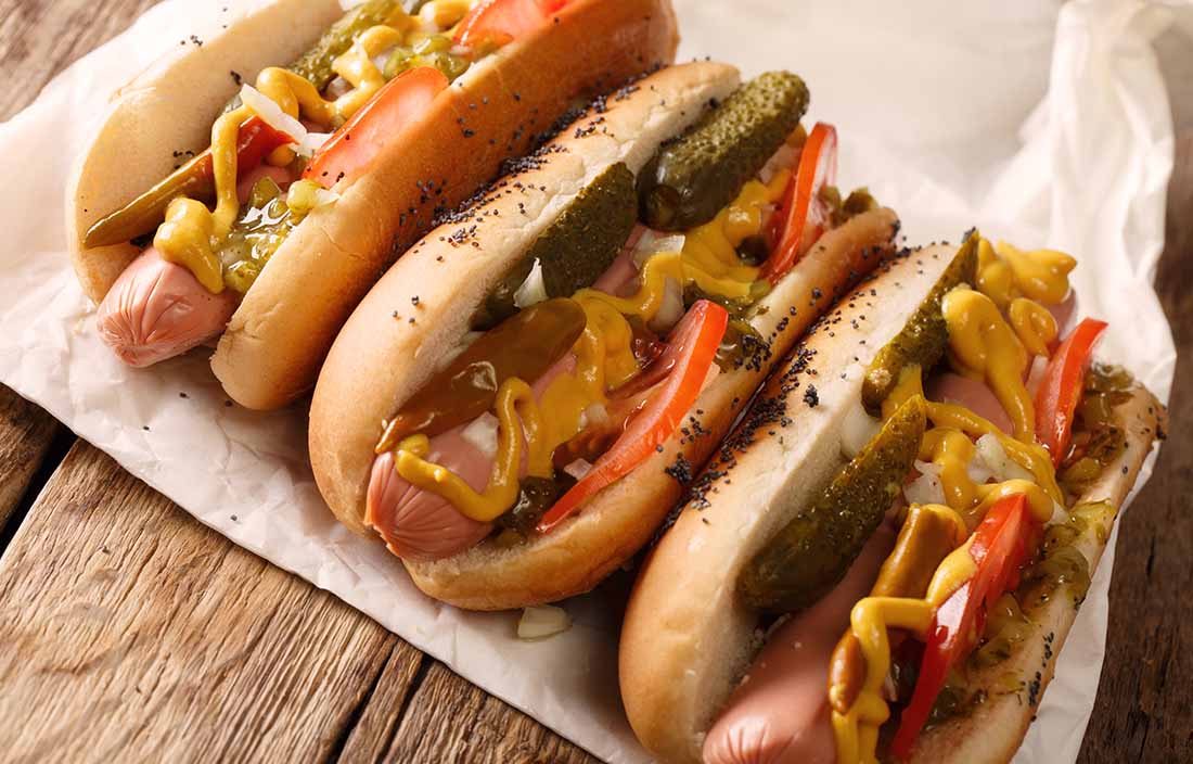 Image of three Chicago style hotdogs on paper. 