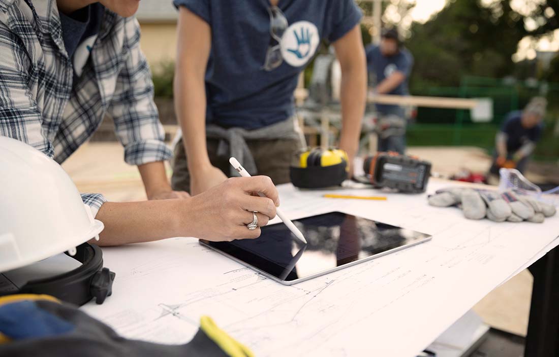 Construction workers standing at a table looking at an iPad