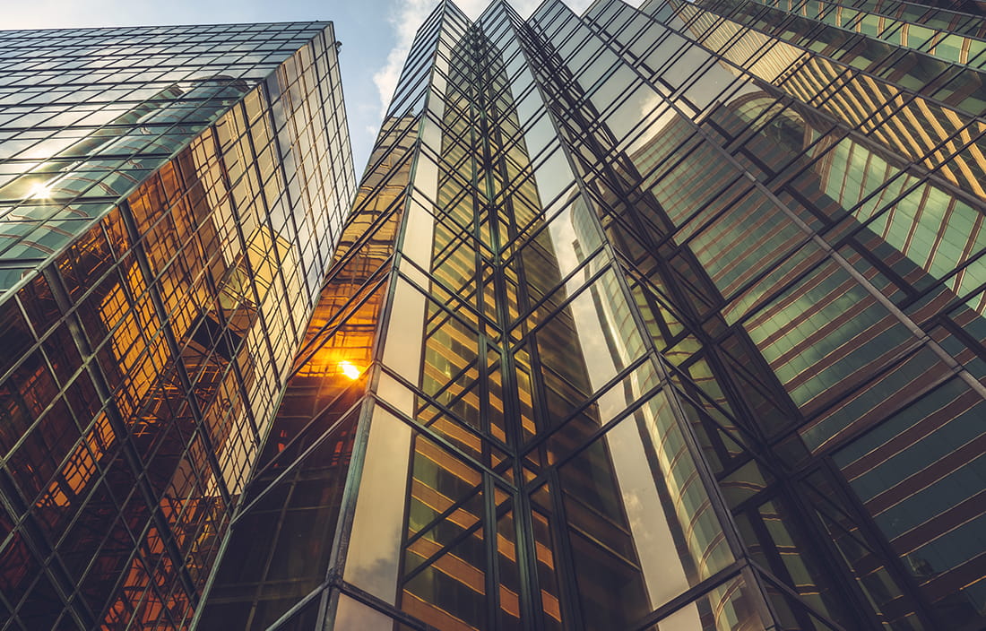 Angled shot of a skyscraper building with the sun reflecting on the glass.