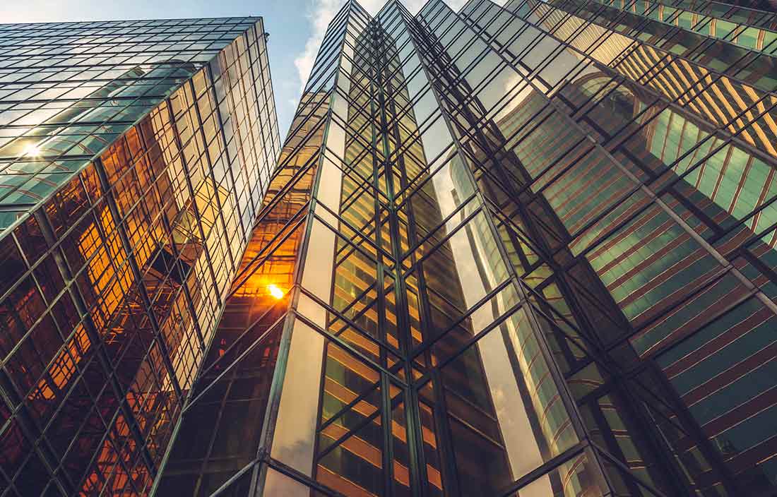 Angled shot of a skyscraper building with the sun reflecting on the glass.