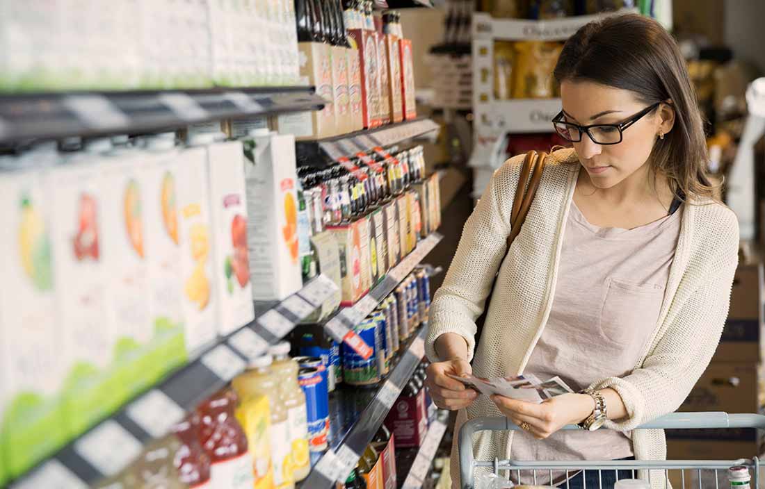 Shopper looking at products in grocery store aisle, considering SKU rationalization and accurate costing data. 