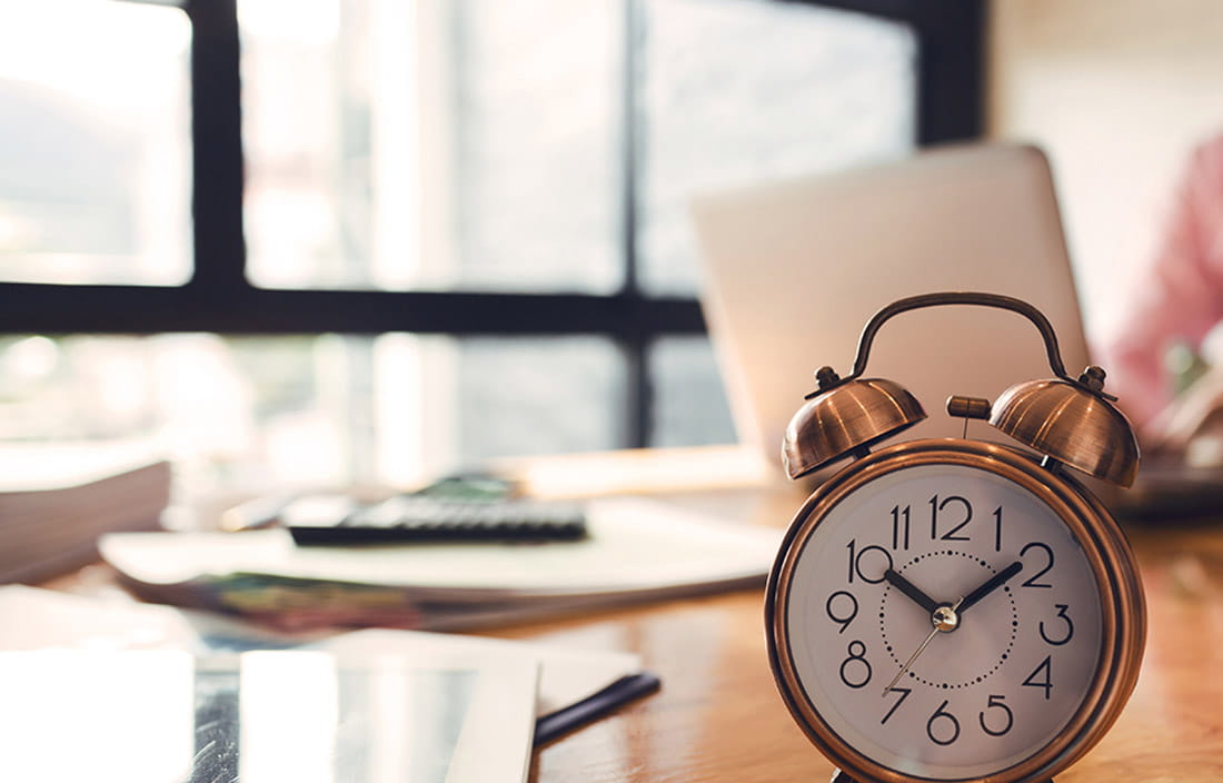 Image of an analog alarm clock on a desk.