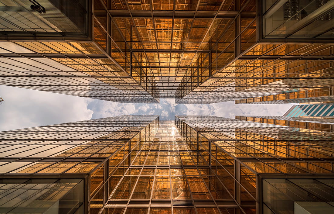 Image of gold skyscrapers from the ground perspective looking up to the sky.