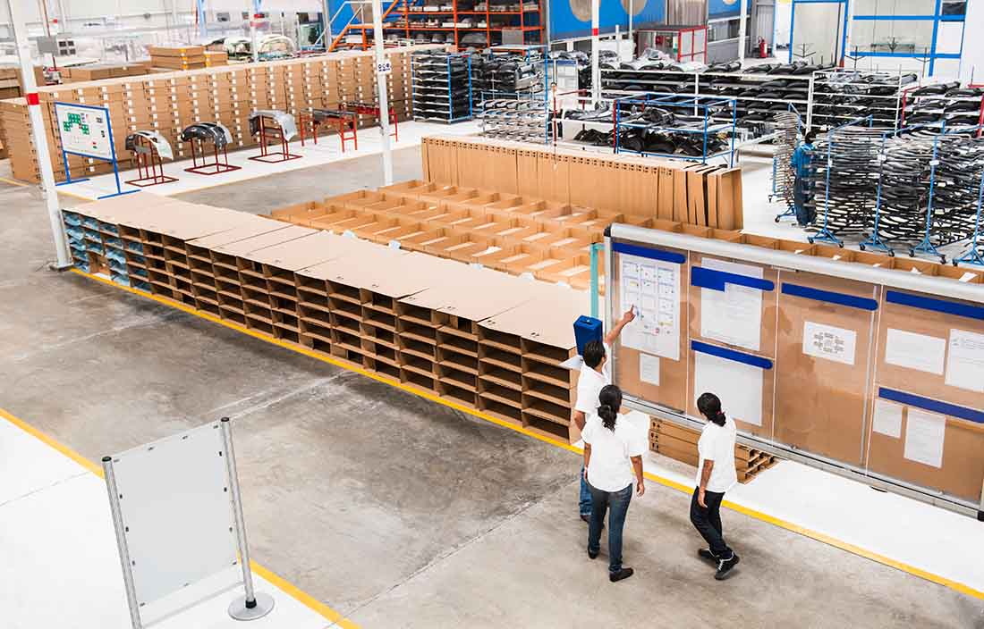 Workers in a Mexico manufacturing facility looking at a board together discussing plans. 