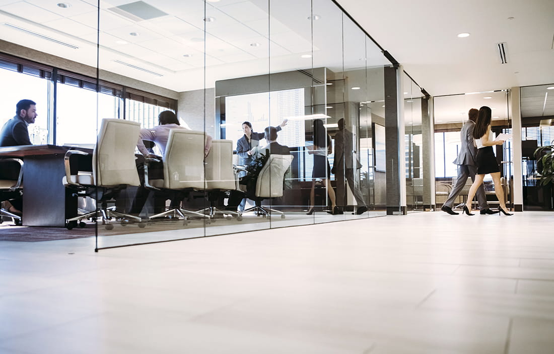 A group of staff members discussing cybersecurity governance inside a glass conference room.