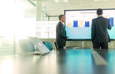 Business professionals looking at charts on a large screen