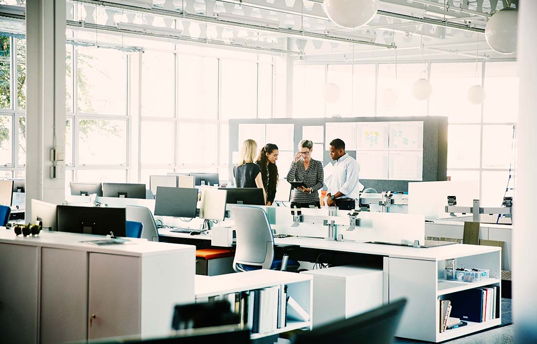 Four people standing in an office looking at an iPad