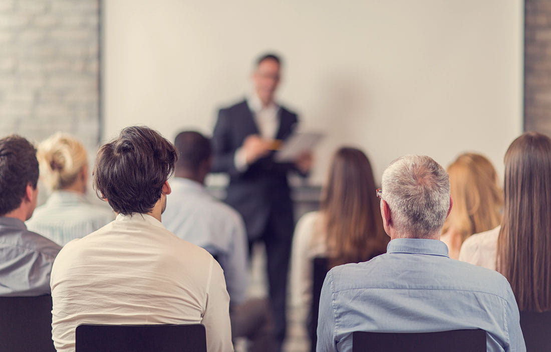 Multiple people sitting, listening to a presenter