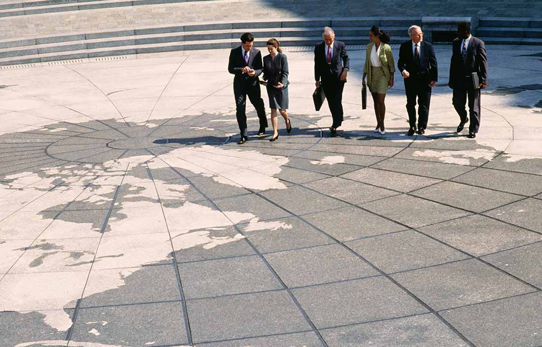 Group of professionals looking at a globe on the concrete side walk.