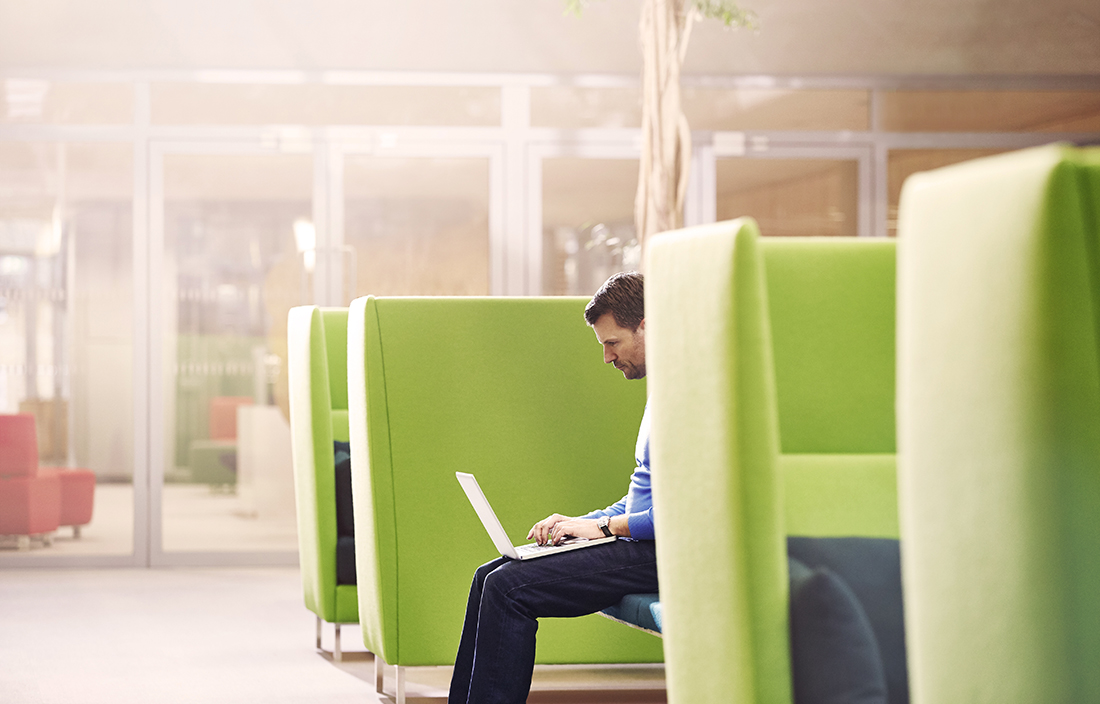 Man on laptop sitting in giant green chair