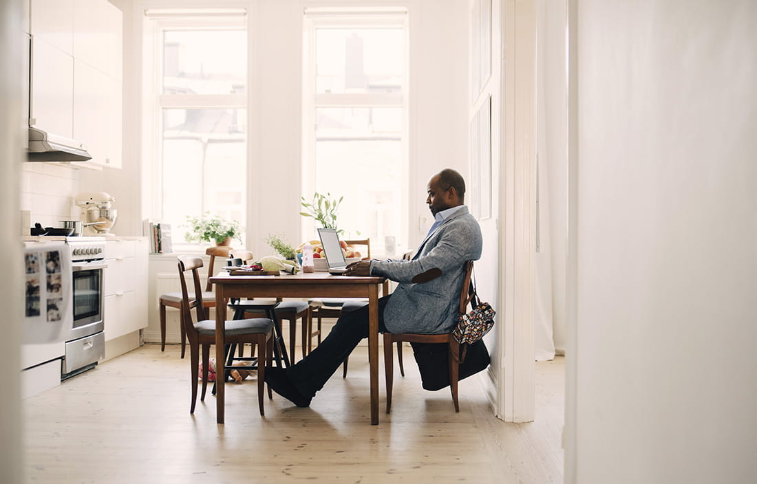 Man sitting at a kitchen table on his laptop