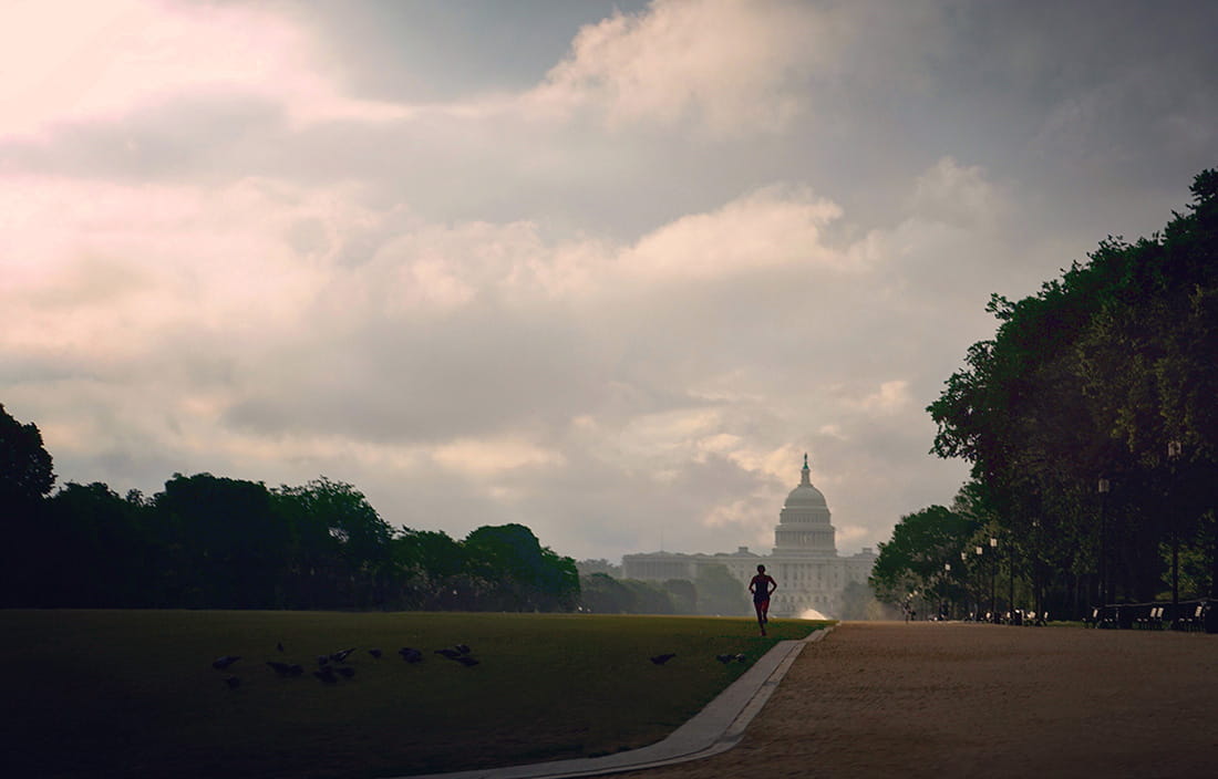 A person running on a walkway outside a government building.