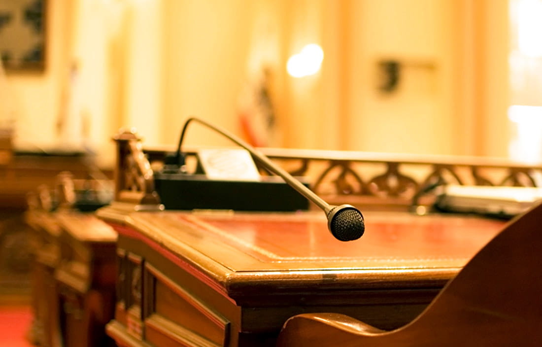 Close-up view of a wooden desk with a microphone hanging above the desk. 