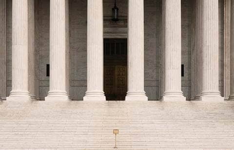 Steps leading up to a government building with column supports.