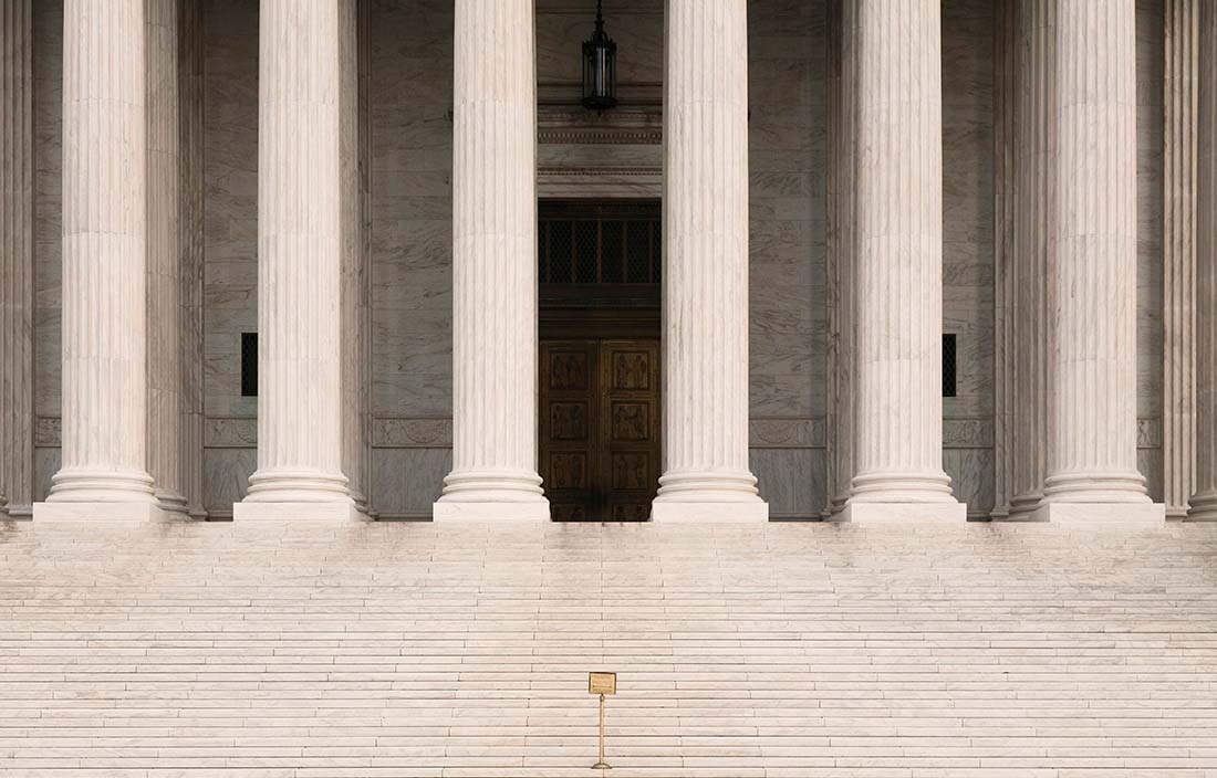 Steps leading up to a historical building with large granite pillars in the front of the building. 