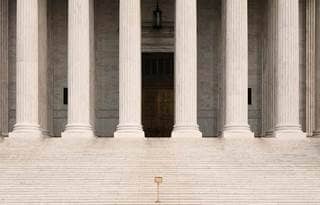 Steps leading up to a historical building with large granite pillars in the front of the building. 
