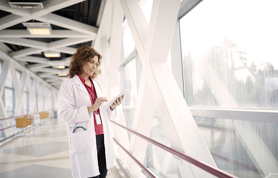 Doctor checking phone on a medical walkway bridge. 