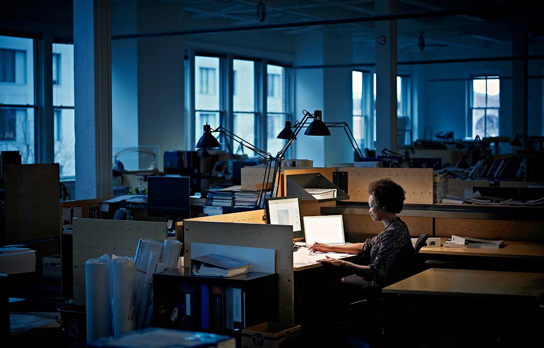 Woman sitting alone at her desk in a dark office