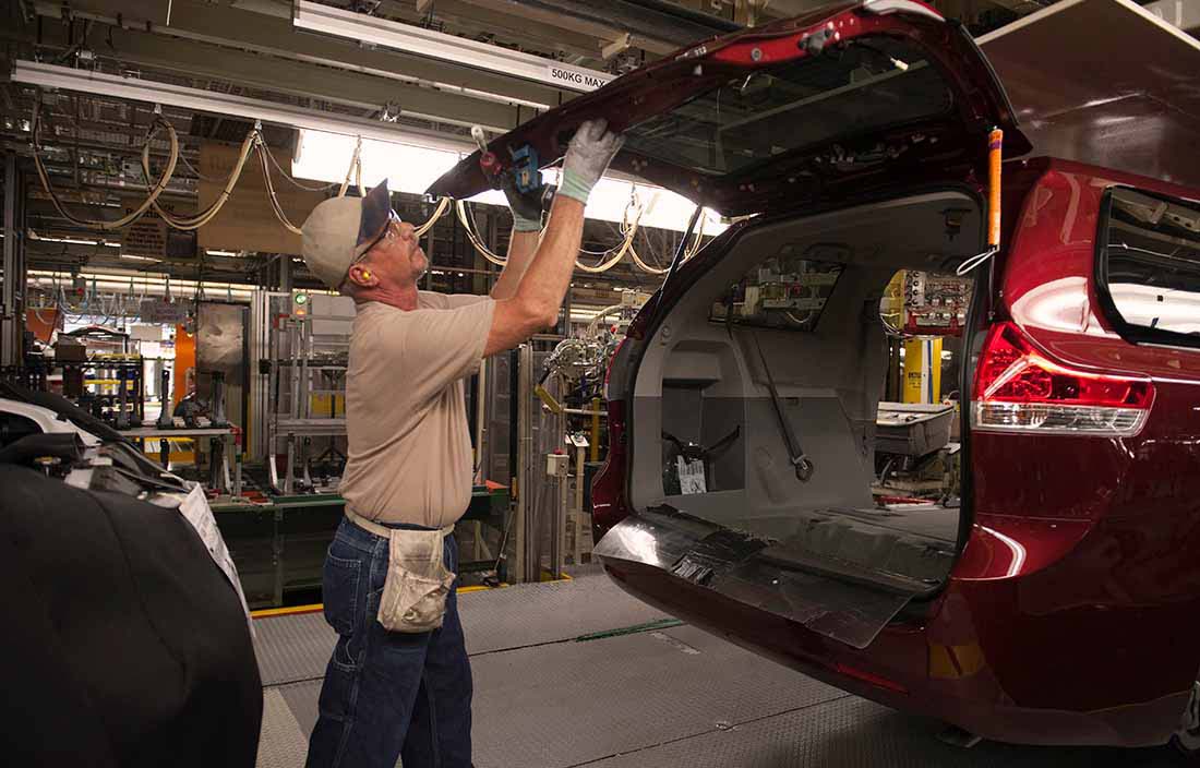 Automotive worker examining the back hatch of an SUV car.