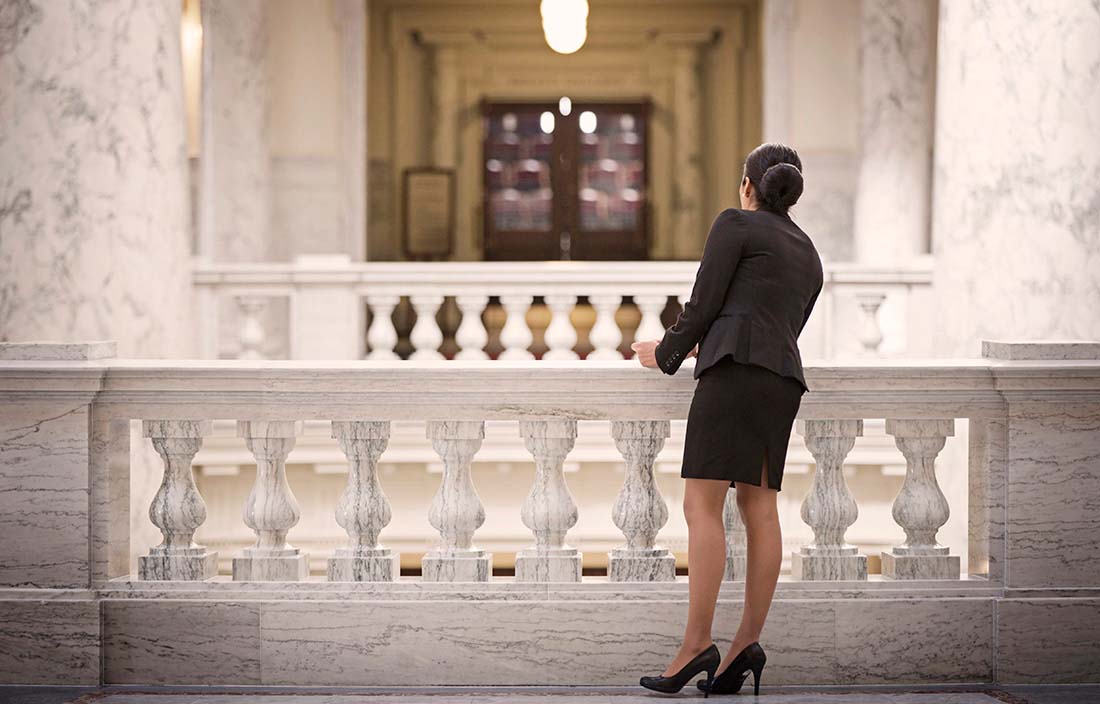 Businesswoman in a government building looking over a marble railing.