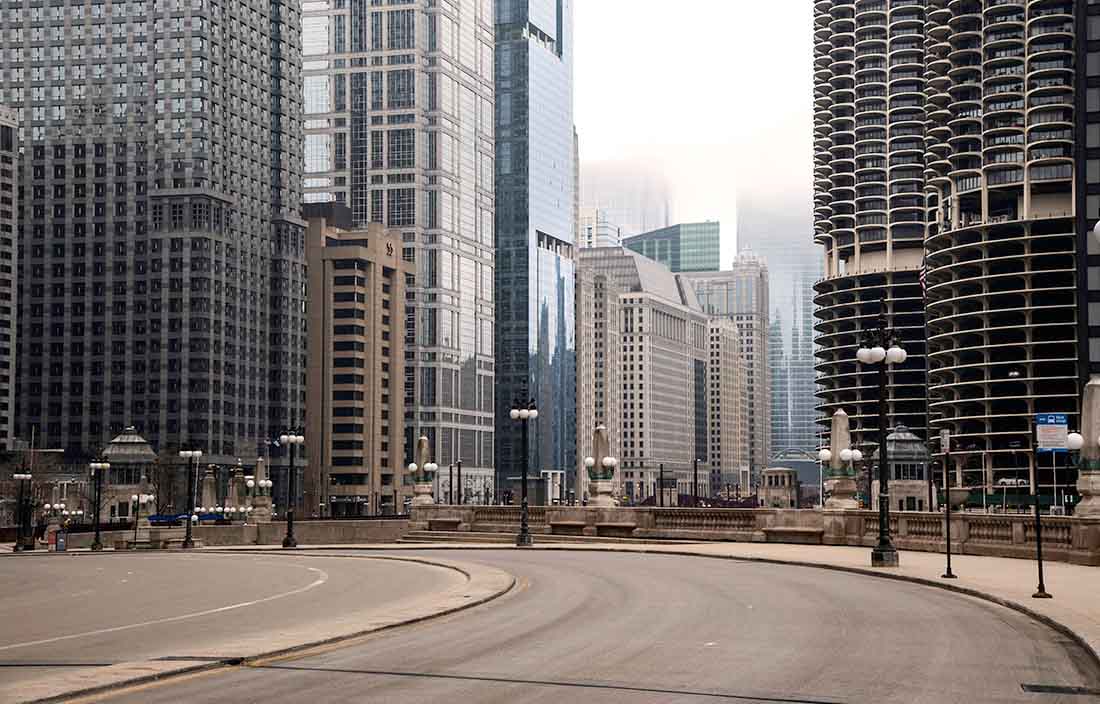 Photo of a left-hand turn for city-street road with city skyscrapers in the background.