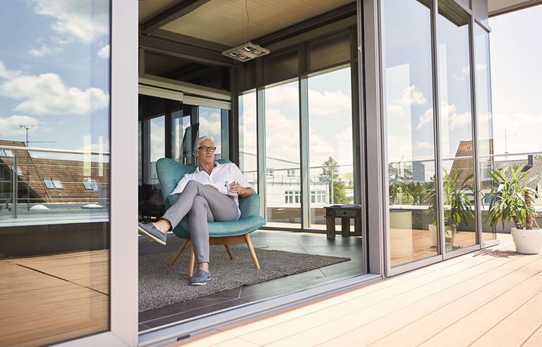 Wealthy middle aged man sitting on a deck with a coffee in his hand.